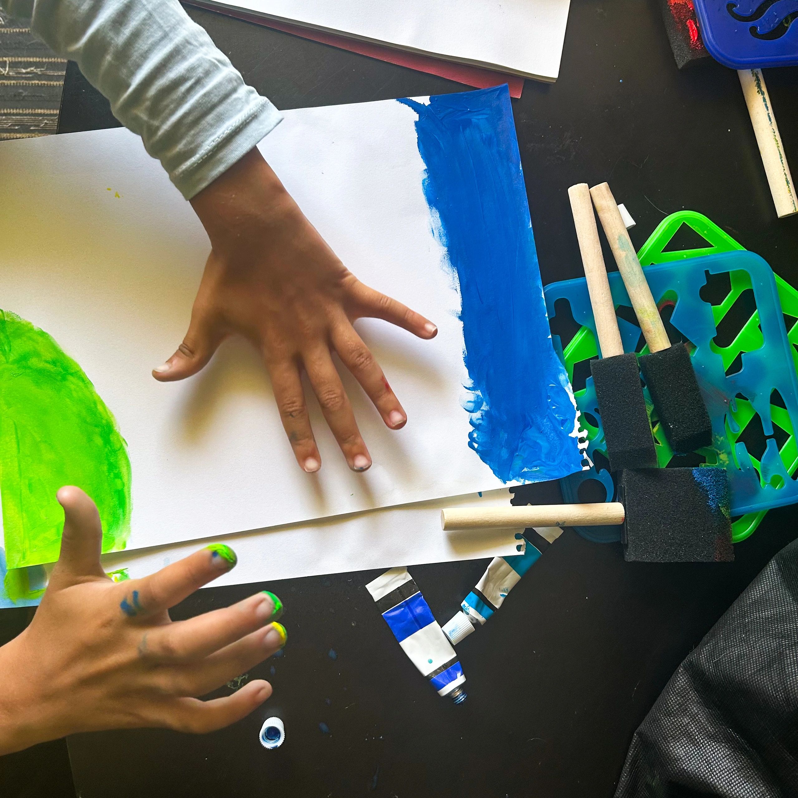 Hands creating a bright painted art project