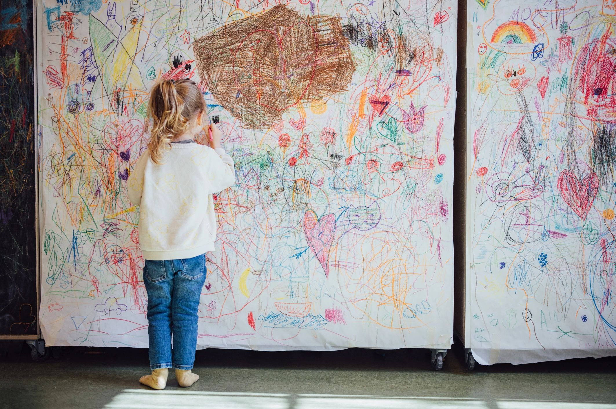 Young artist drawing on a large collaborative art wall